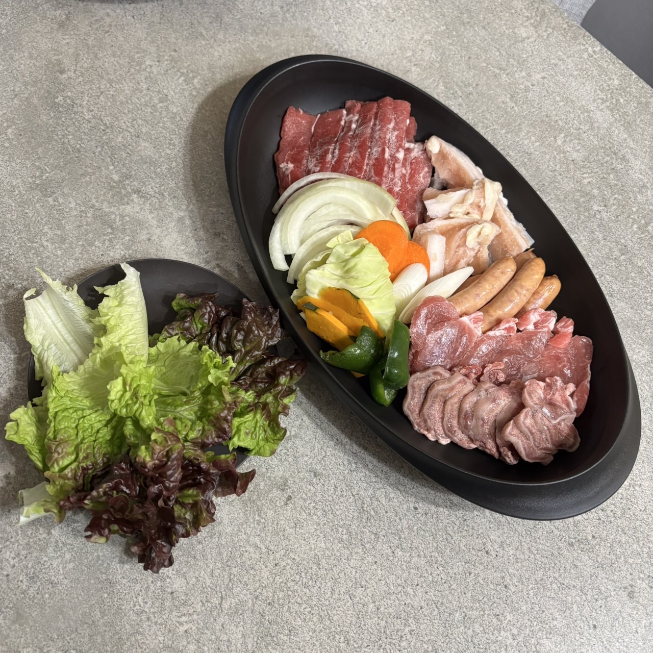ARASの黒い楕円皿に盛った焼肉用の肉と野菜、日常使いで丈夫さを実感するシーン