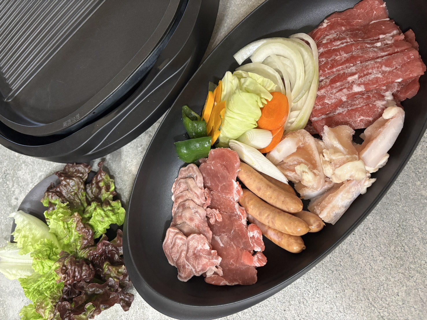 ホットプレート脇のARAS黒皿に盛った焼肉用の肉と野菜をキャンプスタイルで