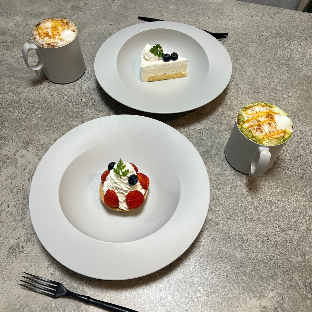白いリムプレートに盛ったケーキ2種とラテのカフェ風シーン
