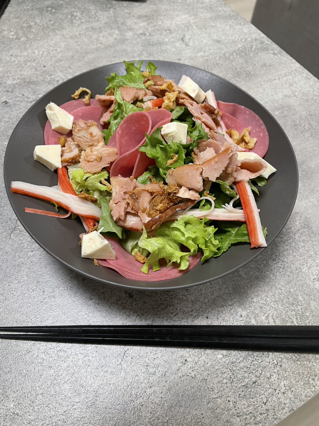 黒いARAS大皿に生ハムやサラダを盛り付けた料理