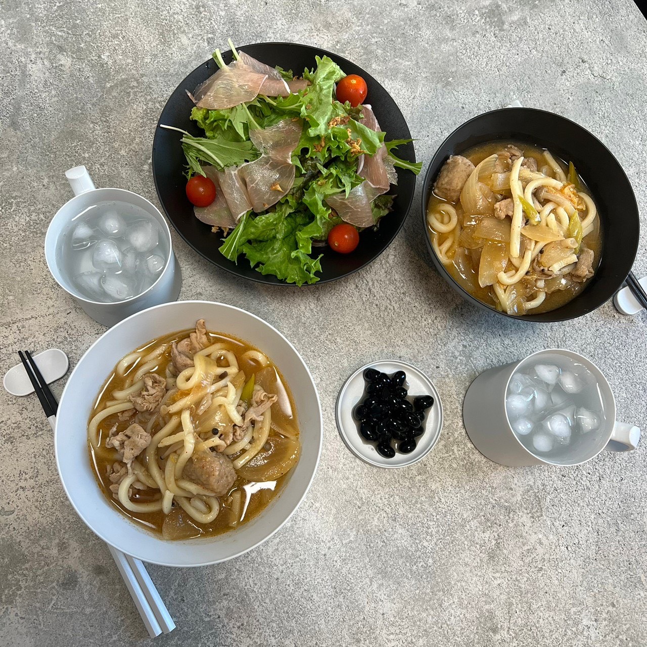 黒いARASの丼に麺料理を盛った食卓