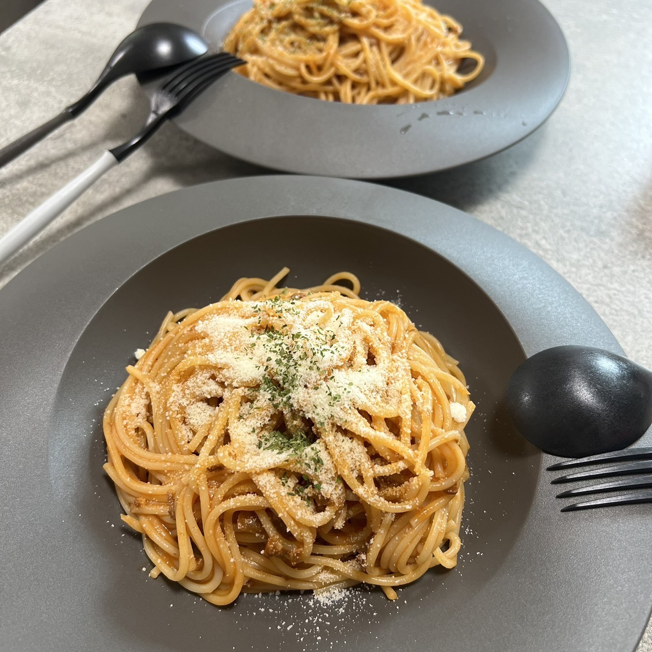 黒いARASプレートにトマトソースパスタを盛った食卓