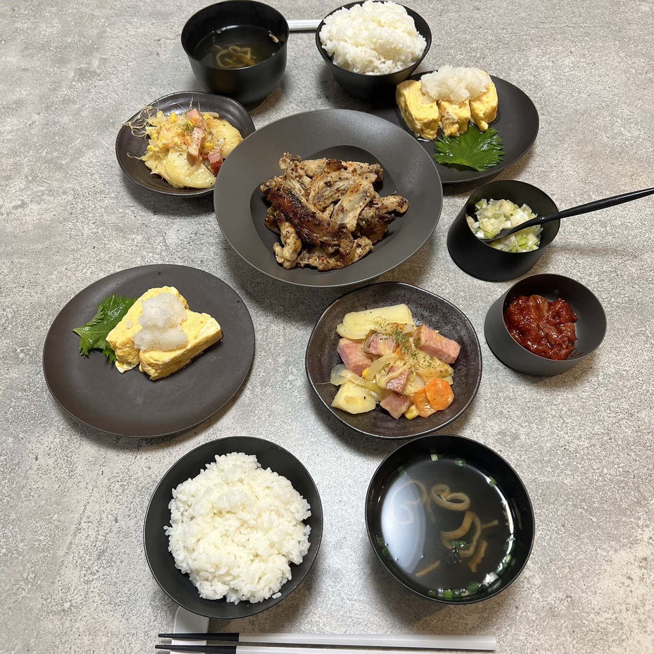 黒いARAS食器に小皿料理を多数並べた食卓